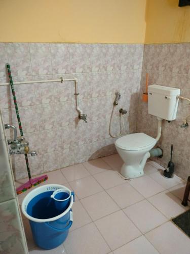 a bathroom with a toilet and a bucket at Dom's Inn in Mangalore