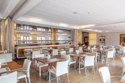 a restaurant with wooden tables and white chairs at Pickalbatros Hôtel Du Golf - Adults Friendly 16 Years Plus- All-Inclusive in Marrakech