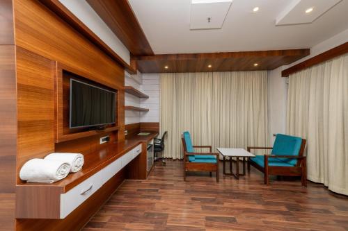 a hospital room with a tv and a table and chairs at Hotel Preethi International in Mysore