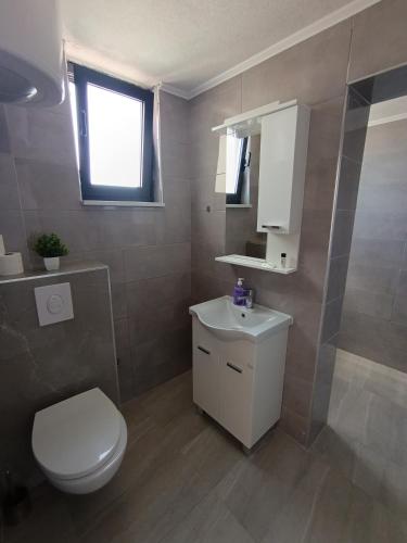 a bathroom with a white toilet and a sink at Apartmani Neum in Neum