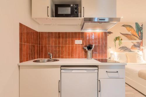 une cuisine avec un évier et un micro-ondes dans l'établissement Lille Grand-place : Functional and quiet studio !, à Lille