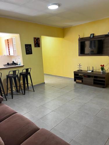 a living room with a couch and a tv and chairs at Apto. em Conceição dos Ouros MG in Conceição dos Ouros