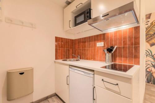 une petite cuisine avec un évier et un micro-ondes dans l'établissement Lille Grand-place : Functional and quiet studio !, à Lille