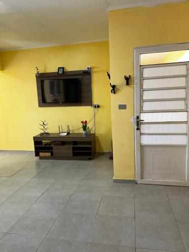 a room with a tv on a yellow wall at Apto. em Conceição dos Ouros MG in Conceição dos Ouros