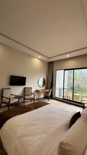 a bedroom with a large bed and a large window at Serene Resorts Naran in Nārān