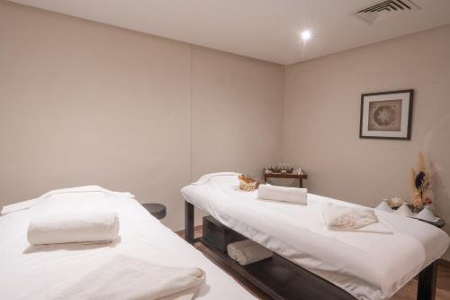 two beds in a room with white walls at Pickalbatros Hôtel Du Golf - Adults Friendly 16 Years Plus- All-Inclusive in Marrakech
