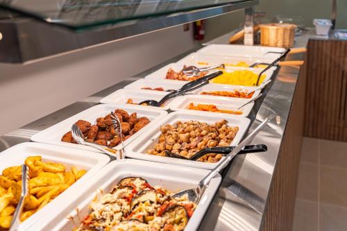 a buffet line with different types of food in trays at Philia Center Suites in Rhodes Town