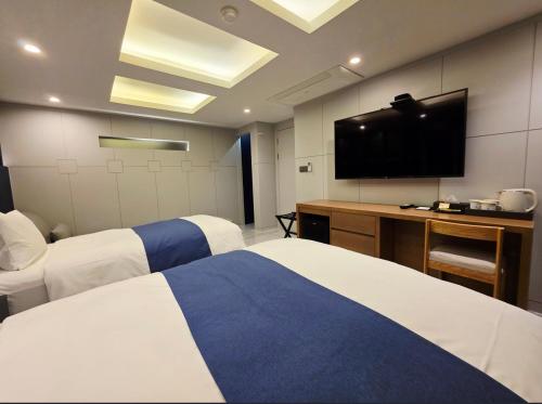 a hotel room with two beds and a flat screen tv at Blueduck hotel in Seoul