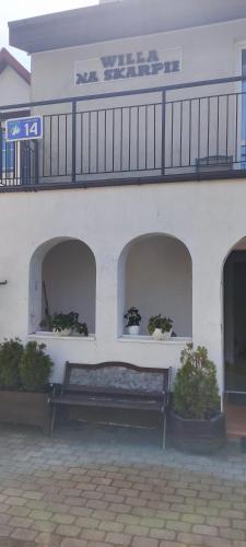 a bench in front of a white building with a balcony at Willa Na Skarpie in Krynica Morska