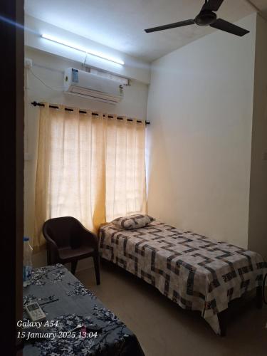 a bedroom with two beds and a chair and a window at Jays Residency - Trinity Sapphire Trivandrum in Trivandrum