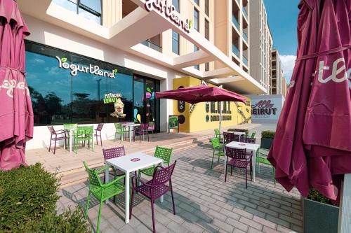 a patio with tables and chairs in front of a building at Luxury 1BR Apartment near Muweilah Sharjah - Sunny Side up in Sharjah Intl