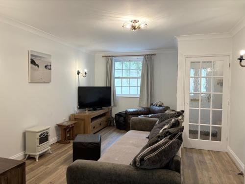 a living room with two couches and a flat screen tv at La Mouette in Mevagissey