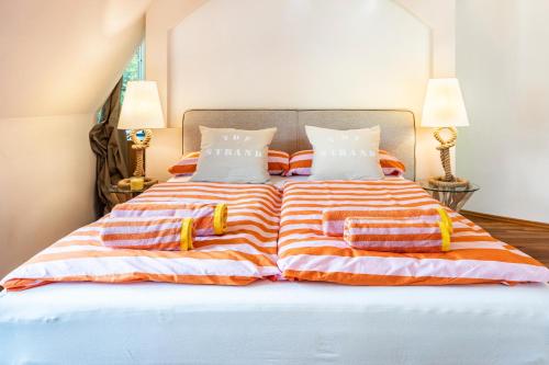 a bed with orange and white striped sheets and pillows at Exklusive Traumvilla mit Sauna in Hamburg