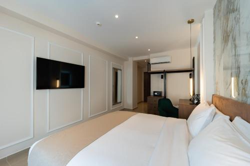 a bedroom with a white bed with a tv on the wall at Philia Center Suites in Rhodes Town