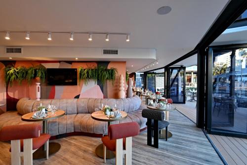 Un restaurante con un sofá, mesas y sillas. en City Lodge Hotel V&A Waterfront, en Ciudad del Cabo