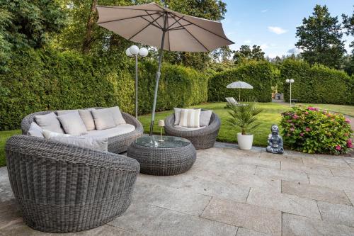 a patio with two wicker chairs and an umbrella at Exklusive Traumvilla mit Sauna in Hamburg