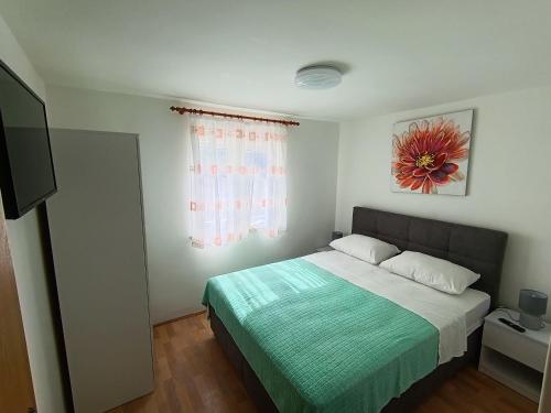 a bedroom with a bed with a green blanket and a window at Apartments Valter Frankovic in Mošćenička Draga