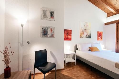 a bedroom with a bed and a chair at Casa Ortensia by Quokka 360 - Cozy house with garden in Monteggio