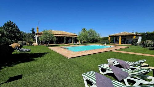 a yard with lounge chairs and a swimming pool at Casa rural Azahares de Marchena in Marchena