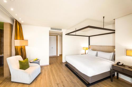a bedroom with a white bed and a chair at Pickalbatros Hôtel Du Golf - Adults Friendly 16 Years Plus- All-Inclusive in Marrakech