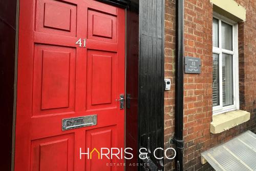 a red door on the side of a brick building at Admirals Rest in Fleetwood