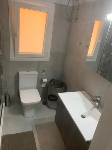 a bathroom with a toilet and a sink and a window at Eva Apartment in Ermoupoli