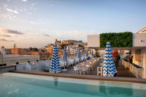 a swimming pool with chairs and umbrellas on a building at Eurostars Puerto de Ibiza in Ibiza Town