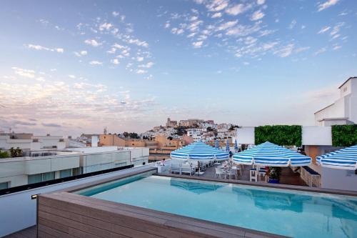 a swimming pool on the roof of a building with umbrellas at Eurostars Puerto de Ibiza in Ibiza Town
