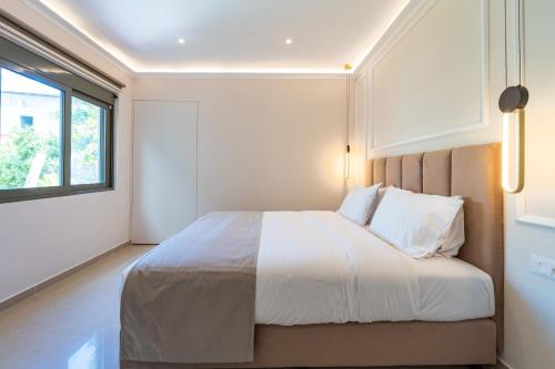 a bedroom with a bed with white sheets and a window at Philia Center Suites in Rhodes Town