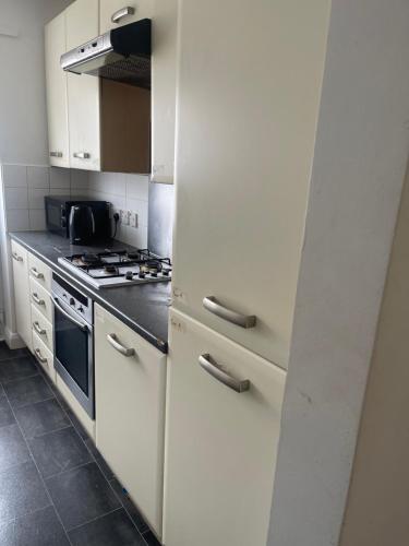 a kitchen with white cabinets and a stove at ComfortVilla in Hornchurch
