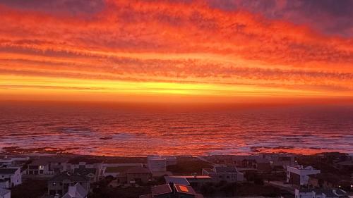 a sunset over the ocean with houses and buildings at Tweede Wind in Yzerfontein