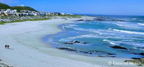 a beach with people walking on the sand and the ocean at Tweede Wind in Yzerfontein