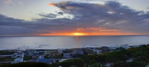 a sunset over a town on the ocean with houses at Tweede Wind in Yzerfontein