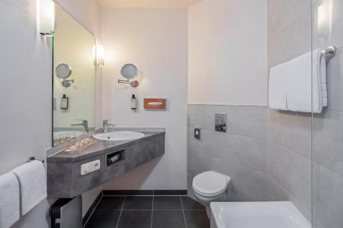 a bathroom with a sink and a toilet at Hotel Oberhausen Neue Mitte affiliated by Meliá in Oberhausen