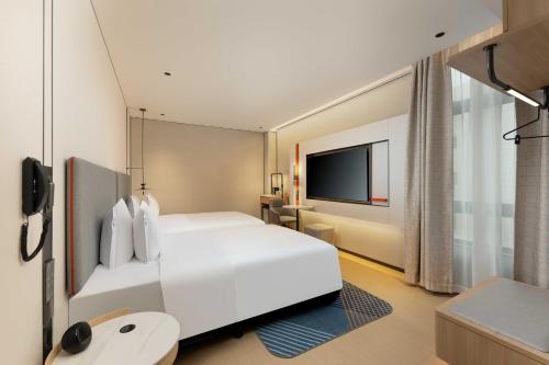 a hotel room with a white bed and a tv at Holiday Inn Express Shanghai PVG Airport Zhuqiao - Free shuttle bus to Pudong Airport and Disneyland in Nanhui