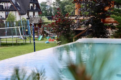 a swimming pool in a yard with a playground at Domki w Białce pod Basenami, 50 m od term i wyciągów in Białka Tatrzanska