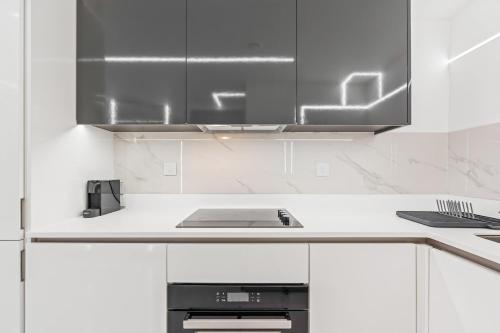 a kitchen with white cabinets and a laptop on a counter at Luxury City Apartment, Walk to O2 Academy & Bullring, Sleeps 4 in Birmingham