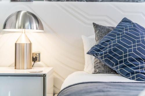 a bed with a blue and white pillow and a lamp at Luxury City Apartment, Walk to O2 Academy & Bullring, Sleeps 4 in Birmingham