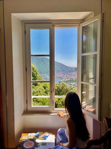 a woman sitting in front of a window looking out at Villa Adelaide Lakeview in Como