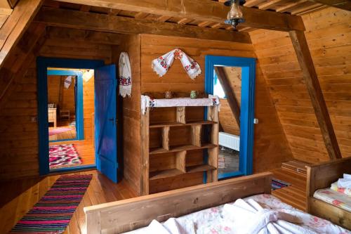 a bedroom in a log cabin with a bed and two windows at Poiana Creasta Cocoșului-Casa Floare De Nu Mă Uita in Breb