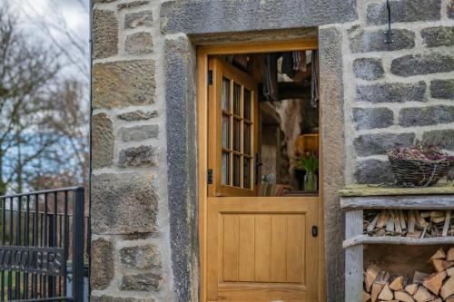 a wooden door in a stone building with a window at Woolcombers in Addingham
