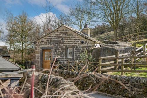 a stone house with a wooden door and a stone wall at Woolcombers in Addingham