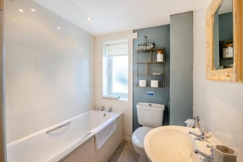 a white bathroom with a tub and a toilet and a sink at Butlers Cottage in Hardraw