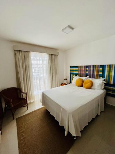 a bedroom with a large white bed with yellow pillows at Pousada Camarote Itaipu in Niterói