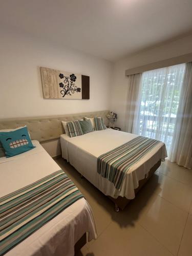 two beds sitting in a room with a window at Pousada Camarote Itaipu in Niterói