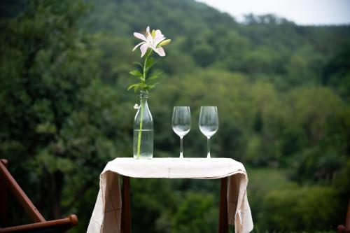 a table with two wine glasses and a flower in a vase at The Sky Imperial Jungle Camp Resort in Kumbhalgarh