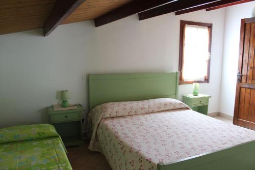 a bedroom with a green bed and a window at Albatros in Capoterra