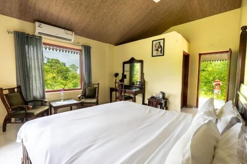 a bedroom with a large white bed and two windows at The Sky Imperial Jungle Camp Resort in Kumbhalgarh
