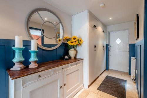 a bathroom with a mirror and a dresser with flowers at Johns Cottage in Hampsthwaite