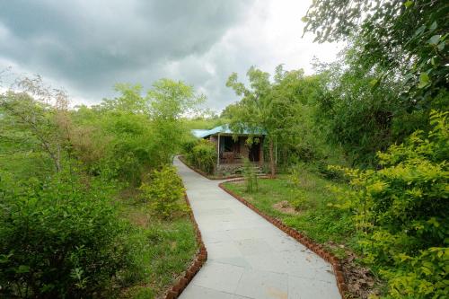 a walkway through a garden with a building in the distance at The Sky Imperial Jungle Camp Resort in Kumbhalgarh